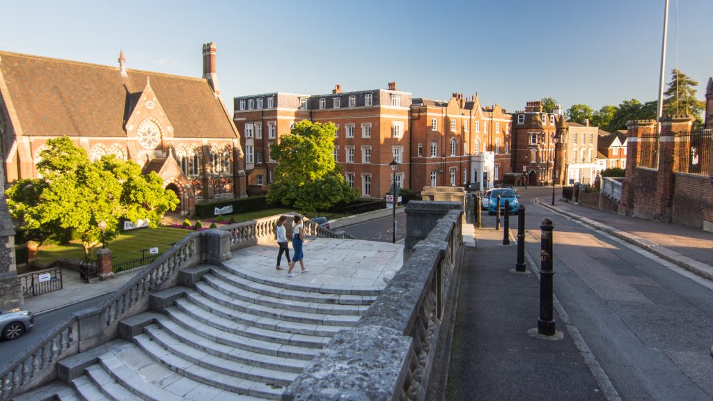 London, England - August 6, 2016: Traffic and pedestrians pass buildings of the independent Harrow School at Harrow-On-The-Hill in West London.